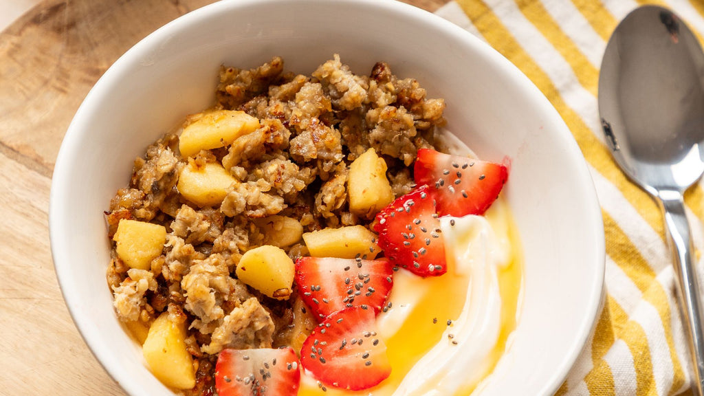 Image of a bowl filled with scrambled oats, apple, strawberries, Greek yoghurt and Hilltop Blossom Honey